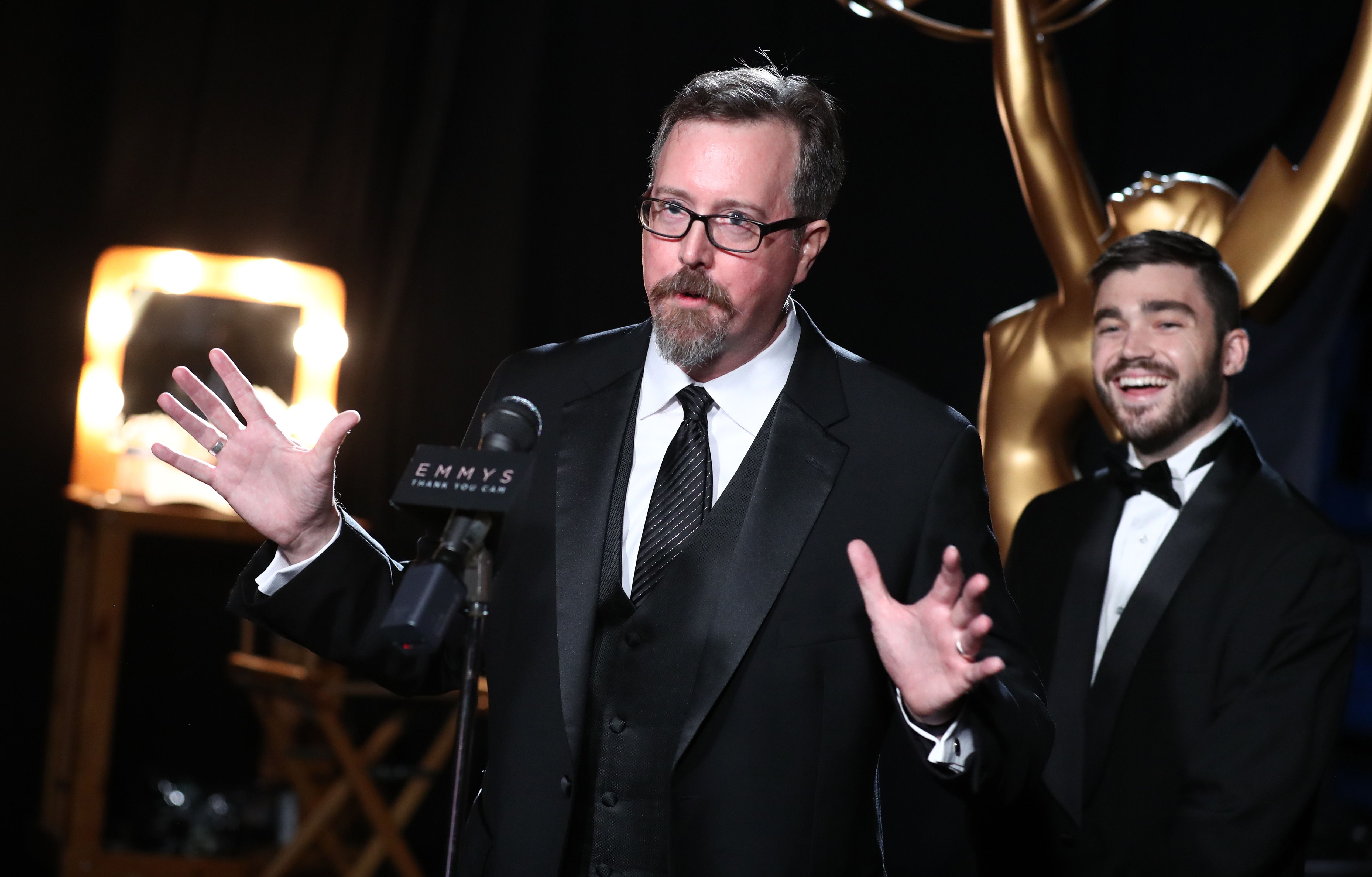 Jon Michaels speaking into a microphone backstage after his Emmy win for the Beatles documentary